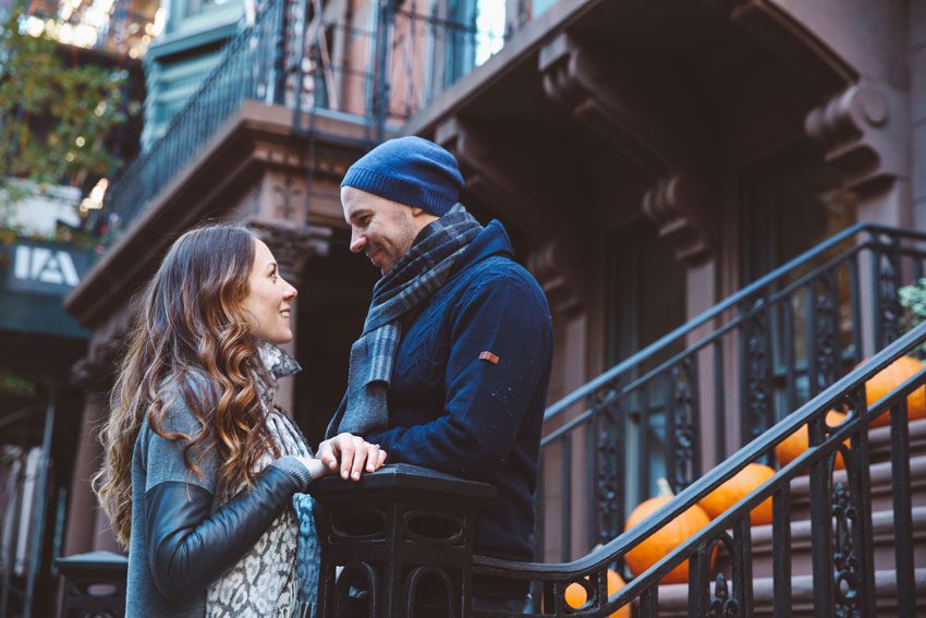 A beautiful couple looking at each other in front of a brownstone