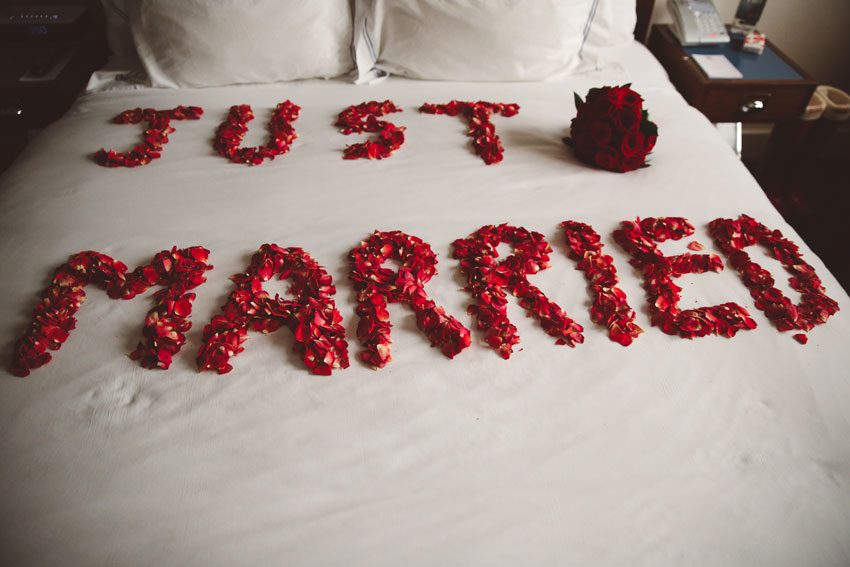 Just married with petals on bed