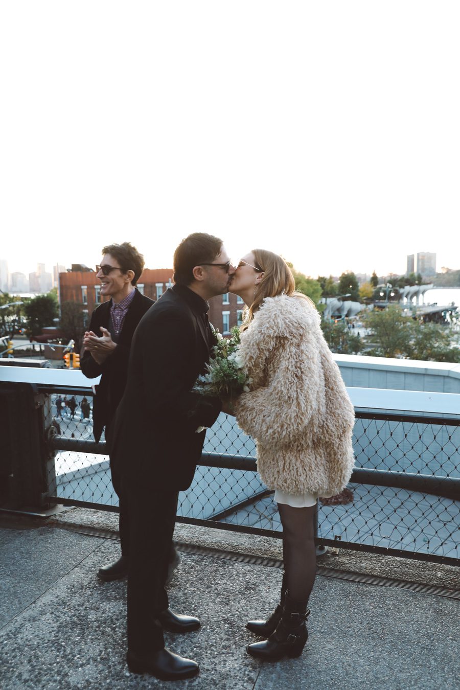 couple kissing and the officiant is in the back