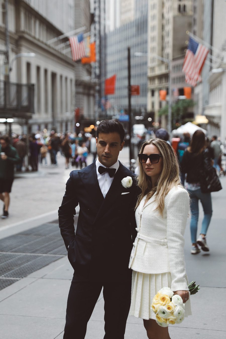 bride and goom looking serious while standing in wall street