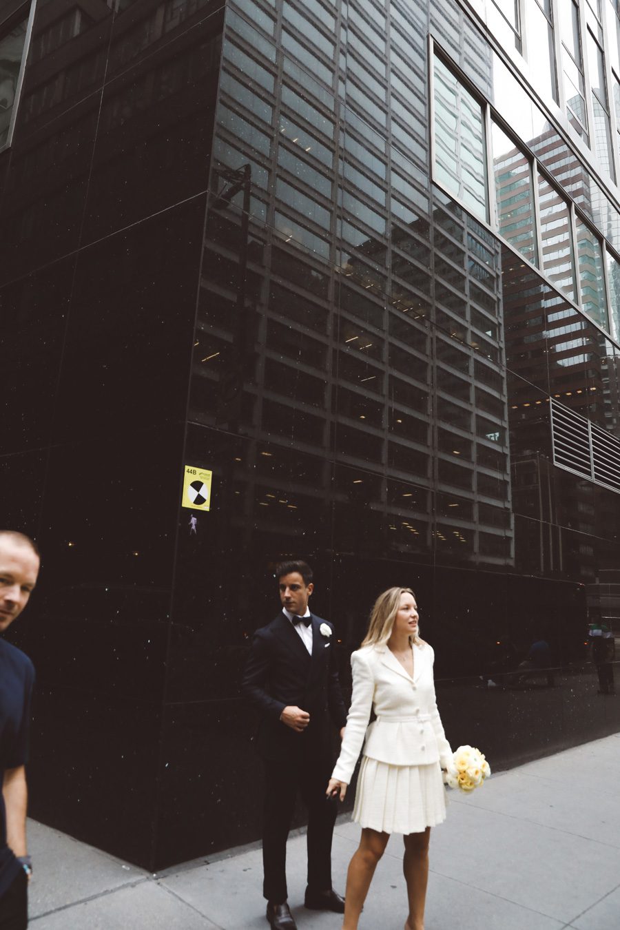 a couple standing on the sidewalk and one man gets in the photo