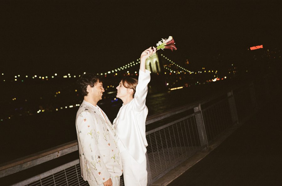 A couple just married at night, she is lifting her bouquet up in the air